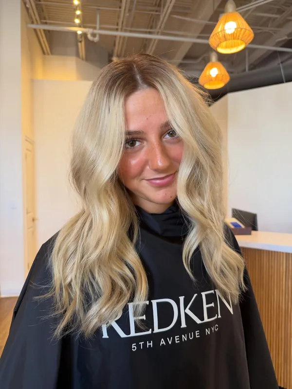 After: bright blonde waves with a soft root, framing the client's face