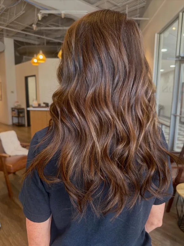 After: brunette waves with warm caramel highlights, from behind